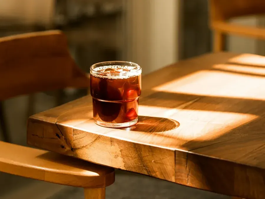 A glass of tea on a sunlit wooden table